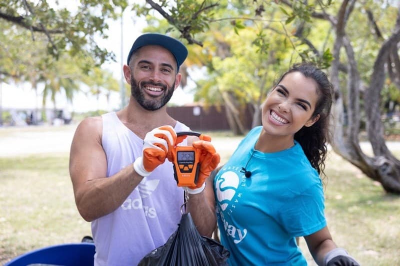 Two volunteers holding up a hanging scale with the day's bag of collected trash