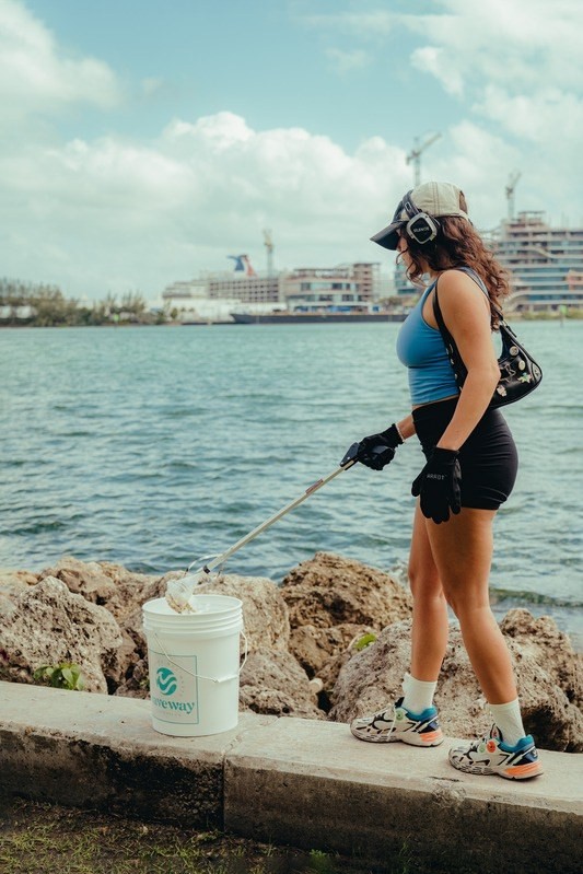 A volunteer working the bay wall with a litter picker and bucket