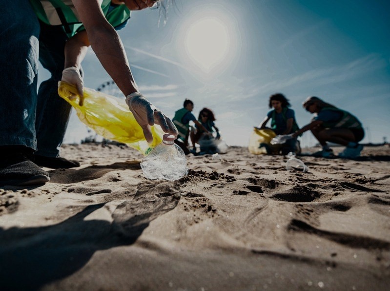 Volunteers crouched on the sand picking litter into yellow bags at sunrise