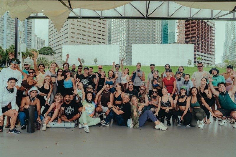 A large group of volunteers posing together with the Miami skyline behind them
