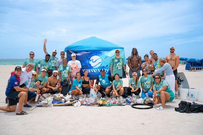 Volunteers gathered under a shade tent on the beach after a cleanup