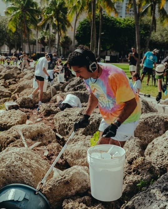 A volunteer in silent-disco headphones clearing debris from the rocks