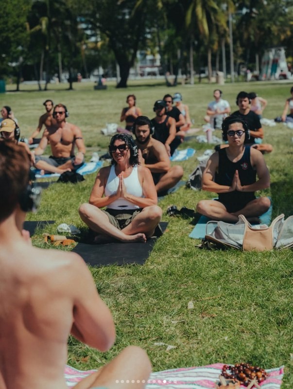Volunteers sitting on the grass in a park before a cleanup begins